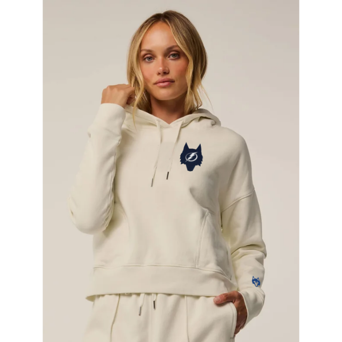 Woman wearing a white hoodie with a blue logo on a plain background