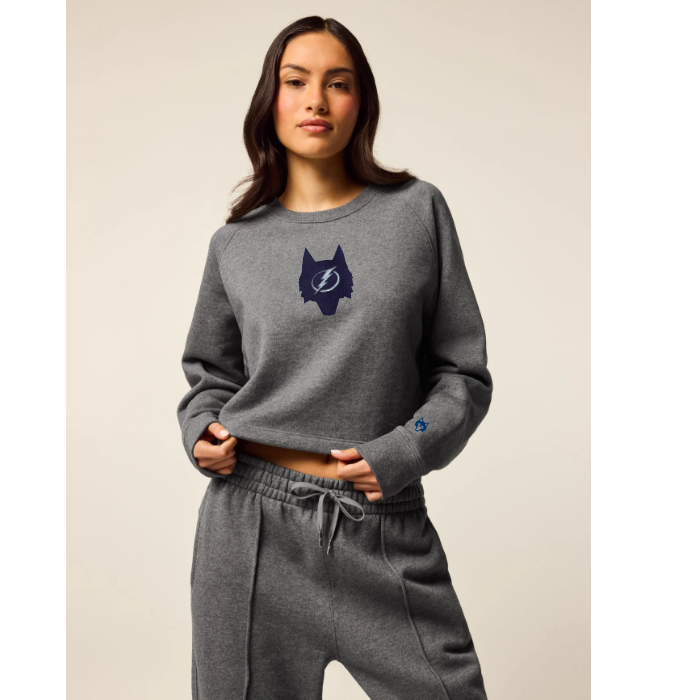 Woman wearing a gray sweatshirt with a logo on a beige background